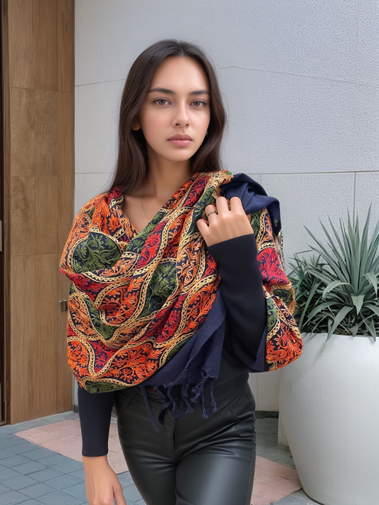 Donna che indossa una sciarpa artigianale in lana con fantasia colorata autunnale, avvolta intorno al collo e spalle, perfetta per l'inverno.