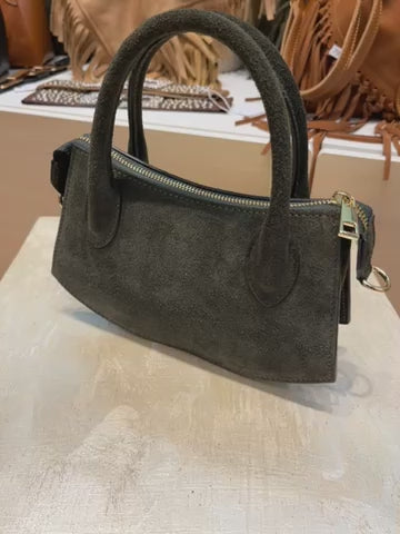 Borsa in pelle scamosciata grigia con maniglie e tracolla regolabile, dettagli metallici dorati, elegante e versatile.
